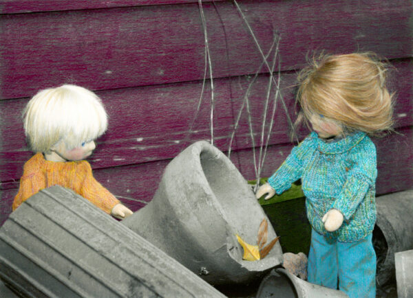 2 wooden dolls looking at discarded junk
