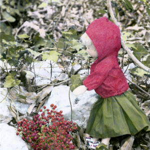 wooden doll with red berries in the snow