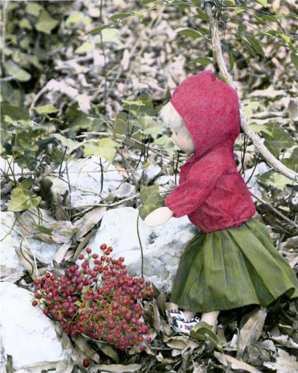 wooden doll with red berries in the snow